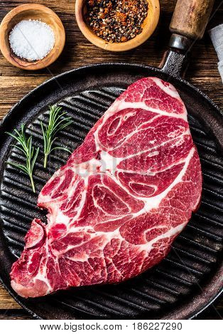 Meat. Raw beef marbled meat steak on vintage cast iron grill pan and spices on wooden rustic background. Top view