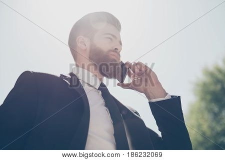 Low Angle View Of A Young Fashionable Bearded Business Man In A Classy Suit Talking On The Phone On