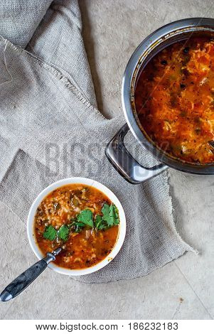 Georgian soup kharcho on a light background. National dish of Georgian jarcho in a bowl and pan. Soup kharcho with linen napkin and spoon.