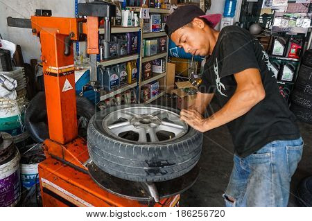 Labuan,Malaysia-May 9,2017:Car tire service mechanic changing car wheel before makes computer wheel balancing on special equipment machine tool in auto repair service in Labuan,Malaysia.