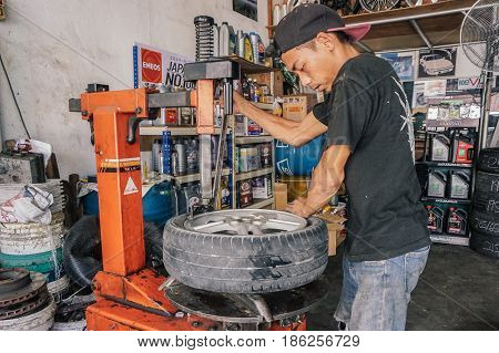 Labuan,Malaysia-May 9,2017:Car tire service mechanic changing car wheel before makes computer wheel balancing on special equipment machine tool in auto repair service in Labuan,Malaysia.