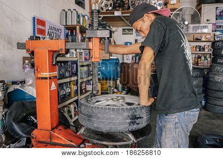 Labuan,Malaysia-May 9,2017:Car tire service mechanic changing car wheel before makes computer wheel balancing on special equipment machine tool in auto repair service in Labuan,Malaysia.