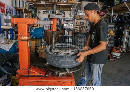 Labuan,Malaysia-May 9,2017:Car tire service mechanic changing car wheel before makes computer wheel balancing on special equipment machine tool in auto repair service in Labuan,Malaysia.