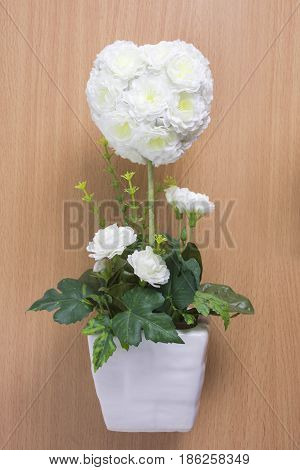 White roses in a ceramic vase on wooden table.