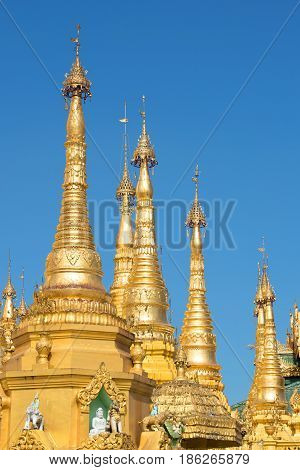 The tops of the golden stupas of the Shwedagon pagoda against the blue sky. Yangon, Myanmar