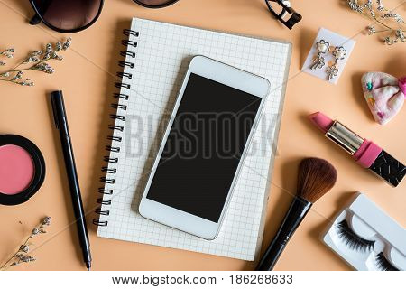 Blank notebook with Various makeup products and smart phone on color background Top view