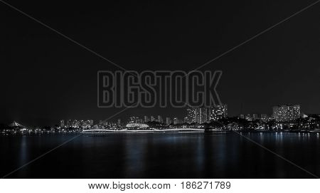 Black and white photo of city lake park in South Korea with skyline in the background taken at night.