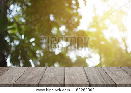 Empty wooden table top and sunny blurred bokeh background for product displa