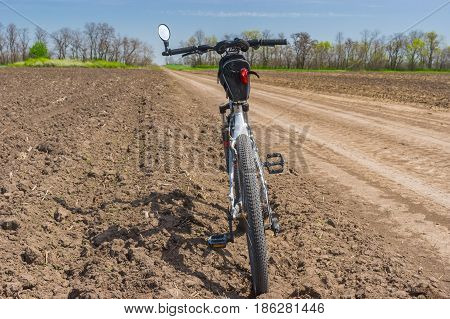 Summer landscape in Ukraine with an earth road between agricultural arable fields and bicycle waiting for the ride