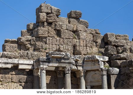 Fragment Of Agora In Ancient Side With Large Stones And Marble Column Pillars Against Blue Sky