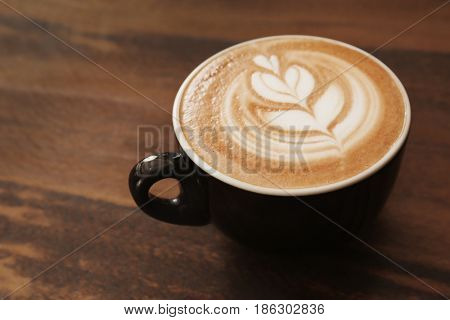 Cup of coffee with latte art on wooden background