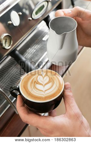Man holding cup of coffee with latte art