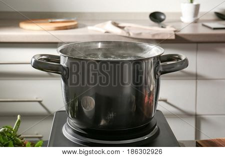 Pan with boiled water on hotplate in kitchen