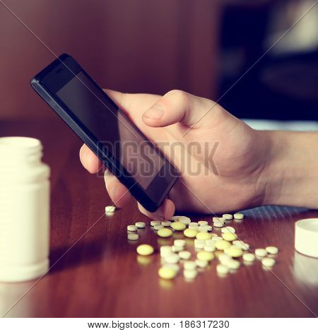 Toned Photo of Person with Cellphone and the Pills on the Table