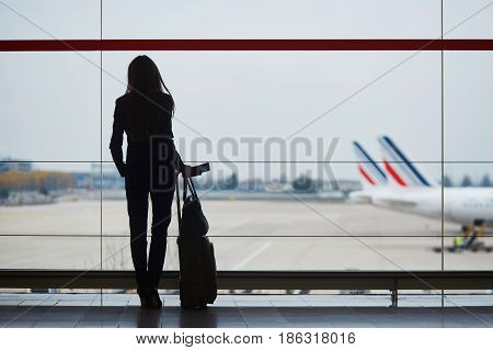 Woman With Hand Luggage In International Airport, Looking Through The Window At Planes