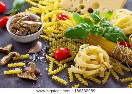 Various Kinds Of Pasta Ingredients With Mushrooms, Basil, Cherry Tomato, Garlic, Pepper, Cheese On T