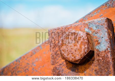 Old Rusty Bolts And Steel Nuts In The Background A Blurred Sky And A Field.