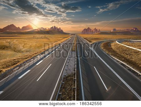 Open highway to the mountain range towards the setting sun. Straight freeway in beautiful desert landscape.