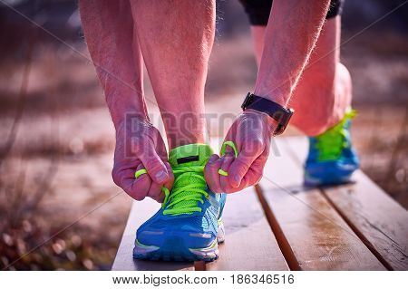 Athlete during training tying shoelaces on sneakers summer.
