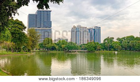 Bangkok, Thailand - December 23 2015: Business district cityscape with Bangkok skyline cloudy sky and reflection. Lumphini Park is a popular place for walks and sport activities