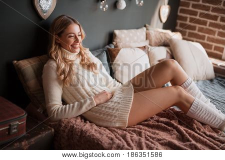 Horizontal indoors shot of young woman lying on the bed and smiling.