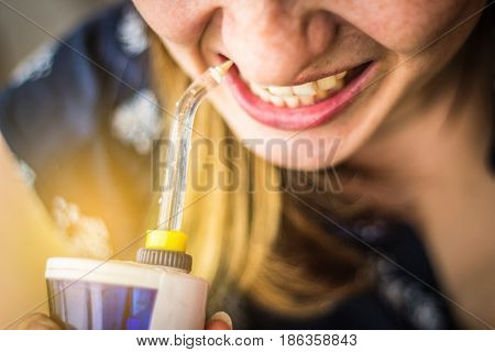 A Woman Using An Oral Irrigator In Bathroom. Selective Focus