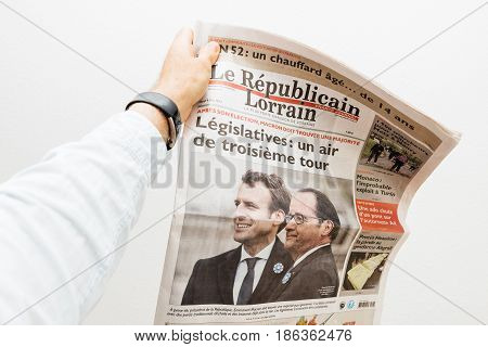 PARIS FRANCE - MAY 10 2017: Man holding le republicain lorrain newspaper front page against white background with the picture of the newly elected French president Emmanuel Macron the 8th President of France