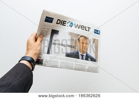 PARIS FRANCE - MAY 10 2017: Man holding Die Welt newspaper front page against white background with the picture of the newly elected French president Emmanuel Macron the 8th President of France