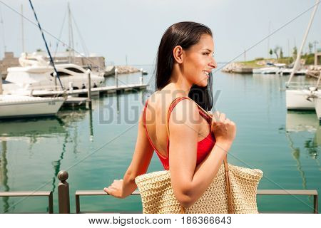 wman walks a city on the beach on hot summer day un beautiful red dress with hat