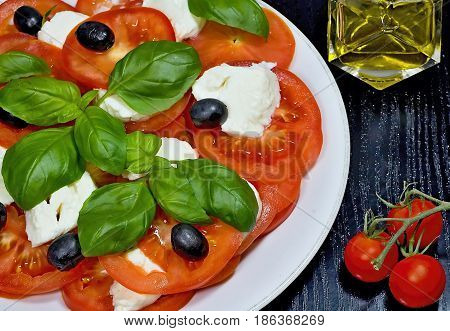 Caprese salad. Classic caprese salad. Italian traditional caprese salad ingredients. Mediterranean food. Caprese salad Tomato and mozzarella with basil leaves on wooden background.
