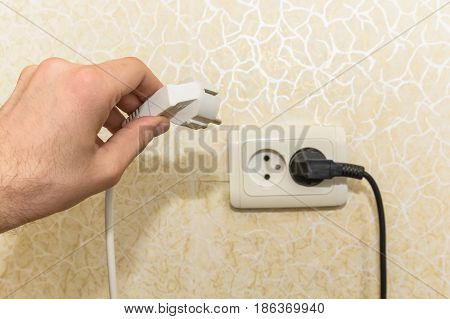 Close-up shot of male hand putting plug into socket