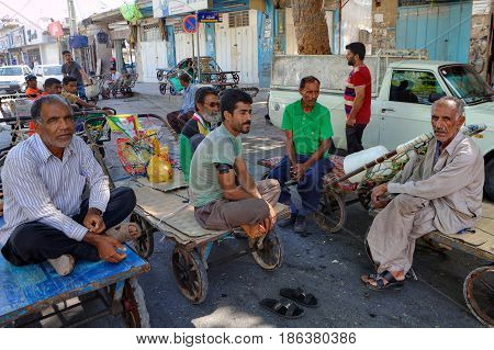 Bandar Abbas Hormozgan Province Iran - 16 april 2017: Several workers of the bazaar are sitting on the platforms of hand carts during a break in work.