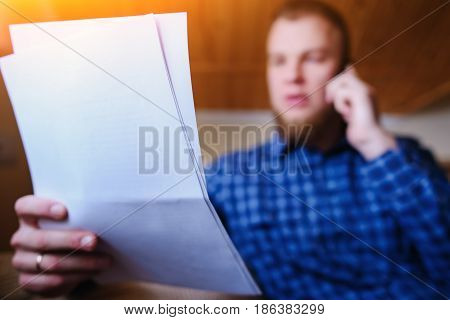 Discussing That Document. Serious Mature Man Holding Paper And Talking On The Mobile Phone While Sit