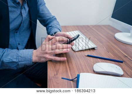 Man in office typing on telephone . Office concept with working environment