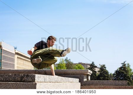Young man jumping over the wall. Parkour in the urban space. Sports in the city. Sport activity.