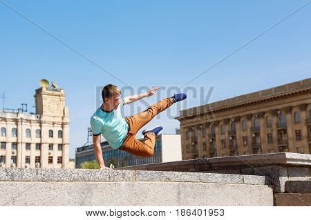 Young man jumps over the wall. Parkour in the urban space. Sport in the city. Sport activity.