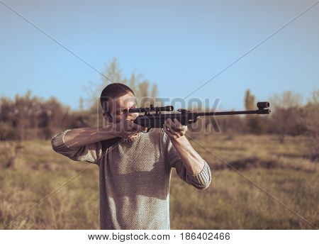 The man takes aim at the target with a sniper strikeball rifle. Retro toning colors. Selective Focus