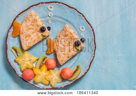 Funny crepes pancakes looks like a fish with fruits for kids breakfast