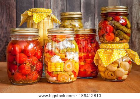 Jars with marinated food and raw vegetables on cutting board.