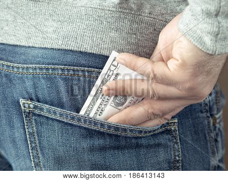 his hand put dollars in jeans pocket or take out from pocket