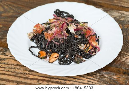 Black spaghetti with seafood and vegetables .