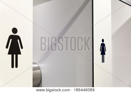 In an public building are women's toilets with white doors and Female Symbol Decals