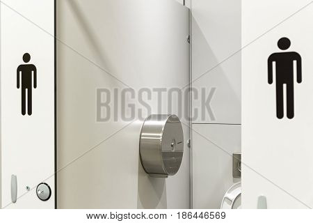In an public building are Men's toilets with white doors and Male Symbol Decals