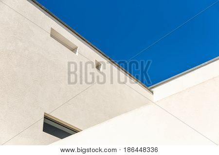 Striking Architectural Corner detail of modern white rendered building with clear blue sky