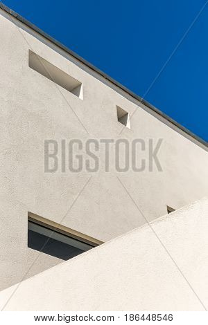 Striking Architectural Corner detail of modern white rendered building with clear blue sky