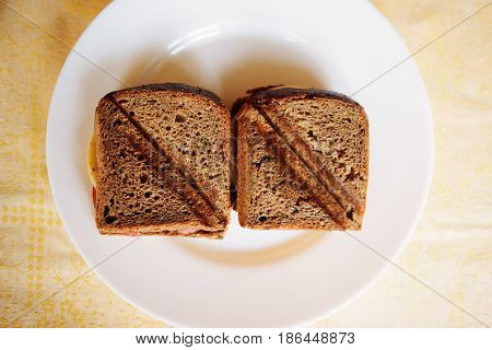toasted ham and cheese sandwich on a white circular plate