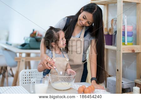 mother and daugthter cooking togather for make bread for dinner in kitchen room kid children
