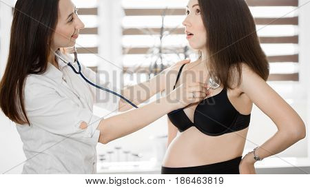 Female Medicine Doctor Holding Stethoscope To Pregnant Woman Standing For Encouragement, Empathy, Ch
