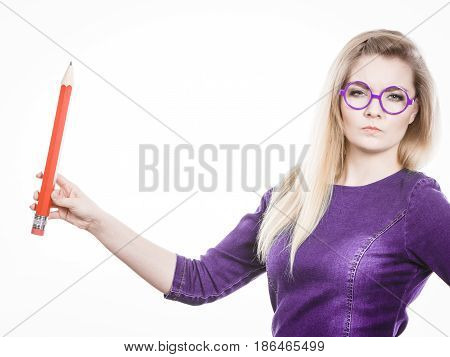 Adult person pensive serious blonde student girl or business woman female teacher wearing nerdy glasses holding big red pencil. Studio shot on white.