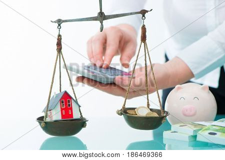Savings or real estate investment concept with house and cash money on scale